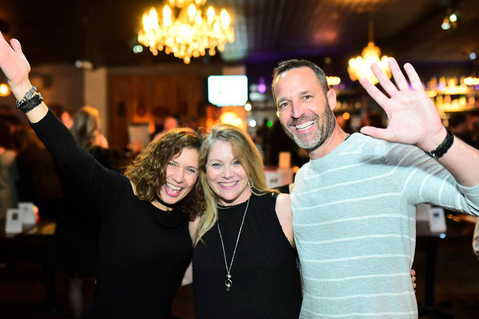 three adults waving at camera